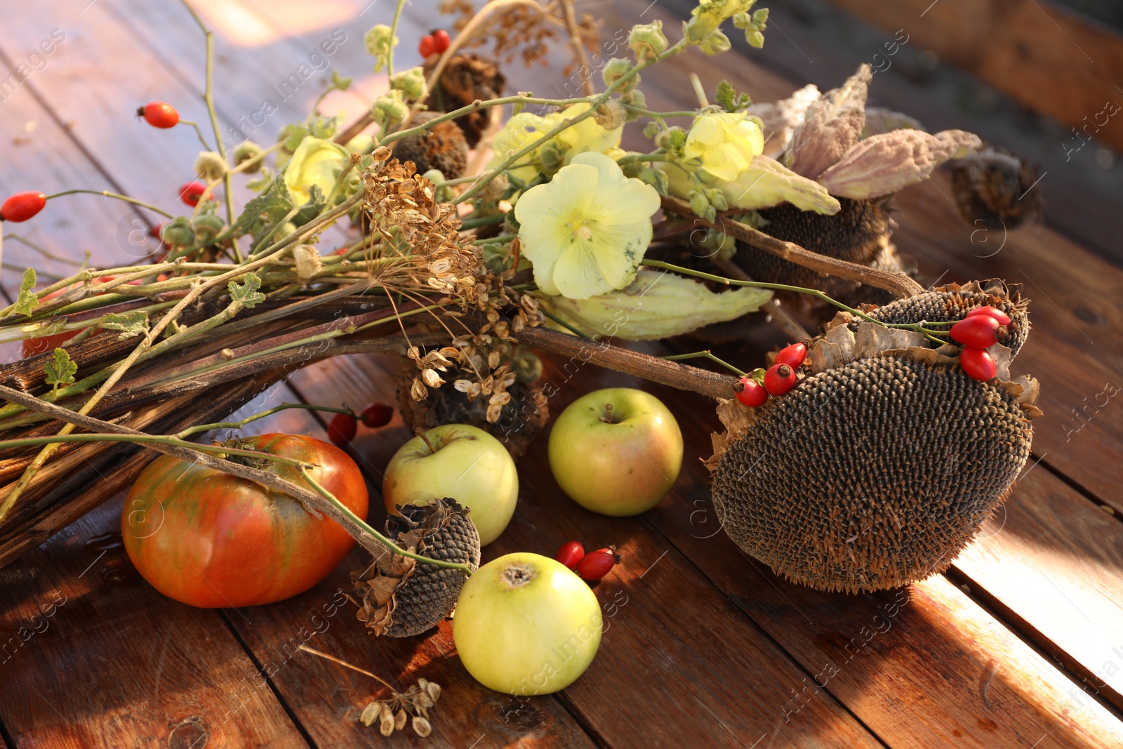 Photo of Composition with beautiful flowers, dry sunflowers and apples on wooden table outdoors, closeup. Autumn atmosphere