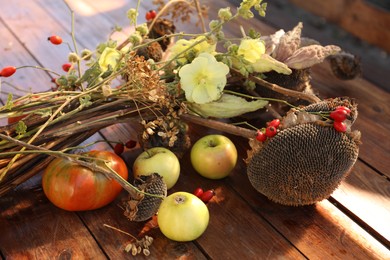 Photo of Composition with beautiful flowers, dry sunflowers and apples on wooden table outdoors, closeup. Autumn atmosphere