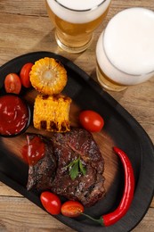 Glasses of beer, delicious fried steak and ingredients on wooden table, flat lay