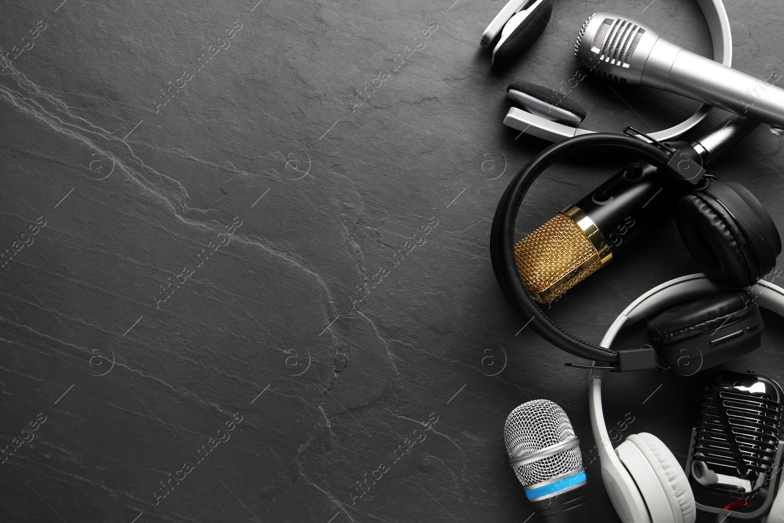 Photo of Different microphones and headphones on grey textured background, flat lay with space for text. Sound recording and reinforcement