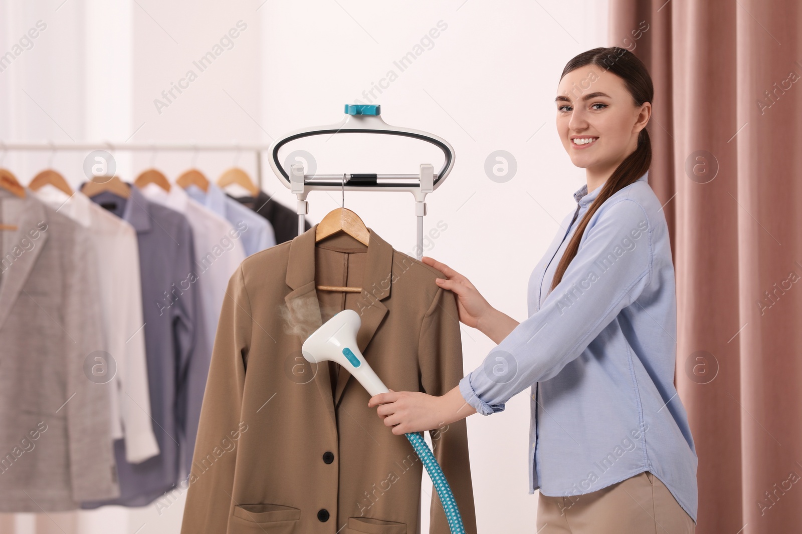 Photo of Woman steaming jacket on hanger in room