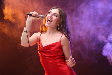 Emotional woman with microphone singing in color lights. Space for text