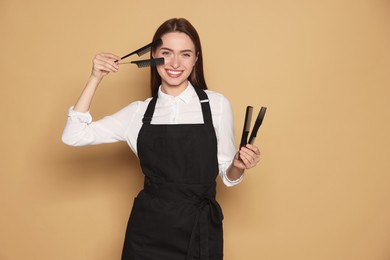 Portrait of happy hairdresser with combs on beige background. Space for text