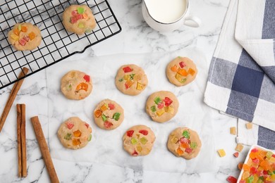 Photo of Unbaked cookies with candied fruits on white marble table, flat lay