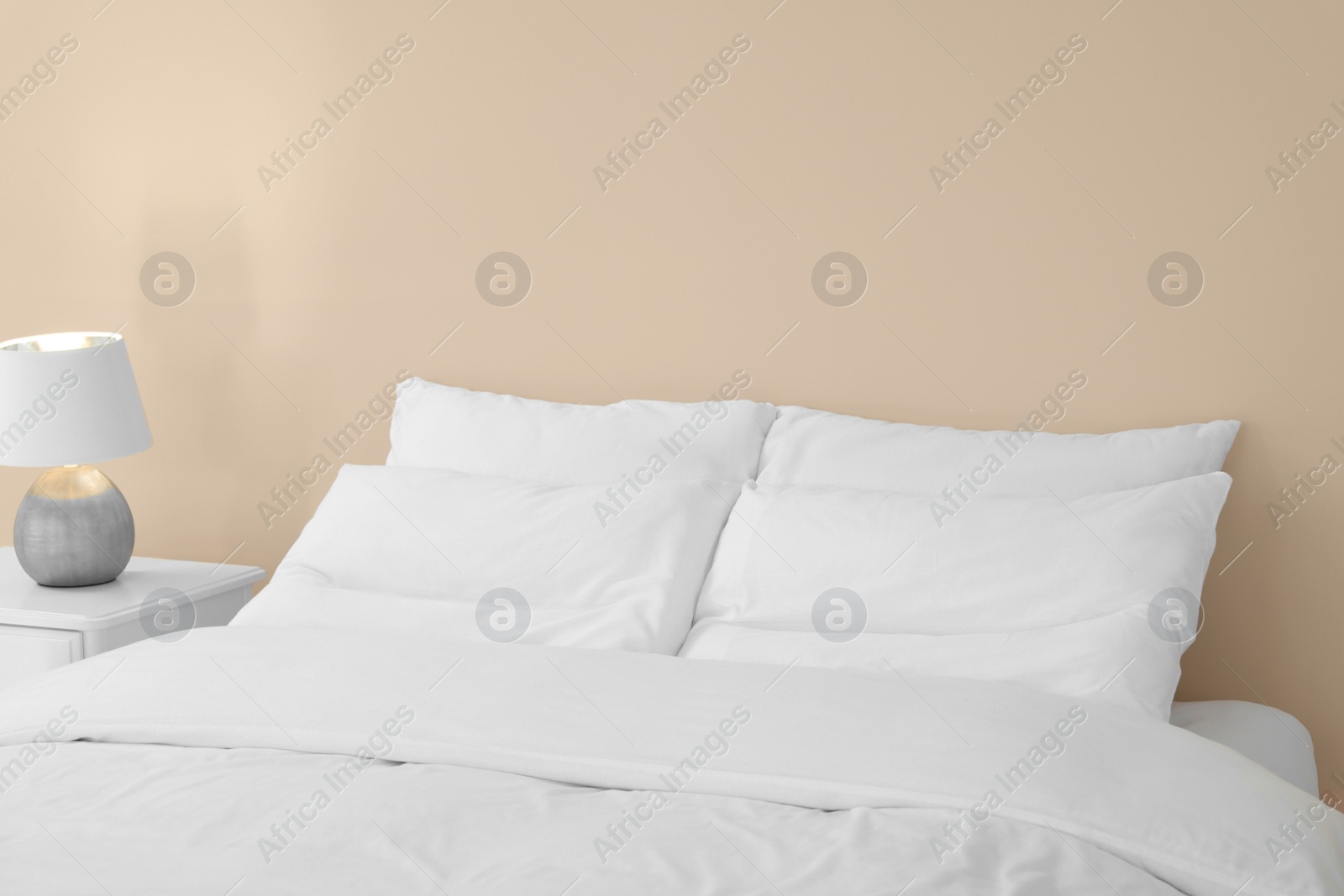 Photo of White soft pillows on cozy bed in room