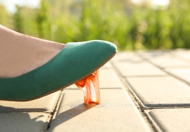 Photo of Woman stepping in chewing gum on sidewalk. Concept of stickiness