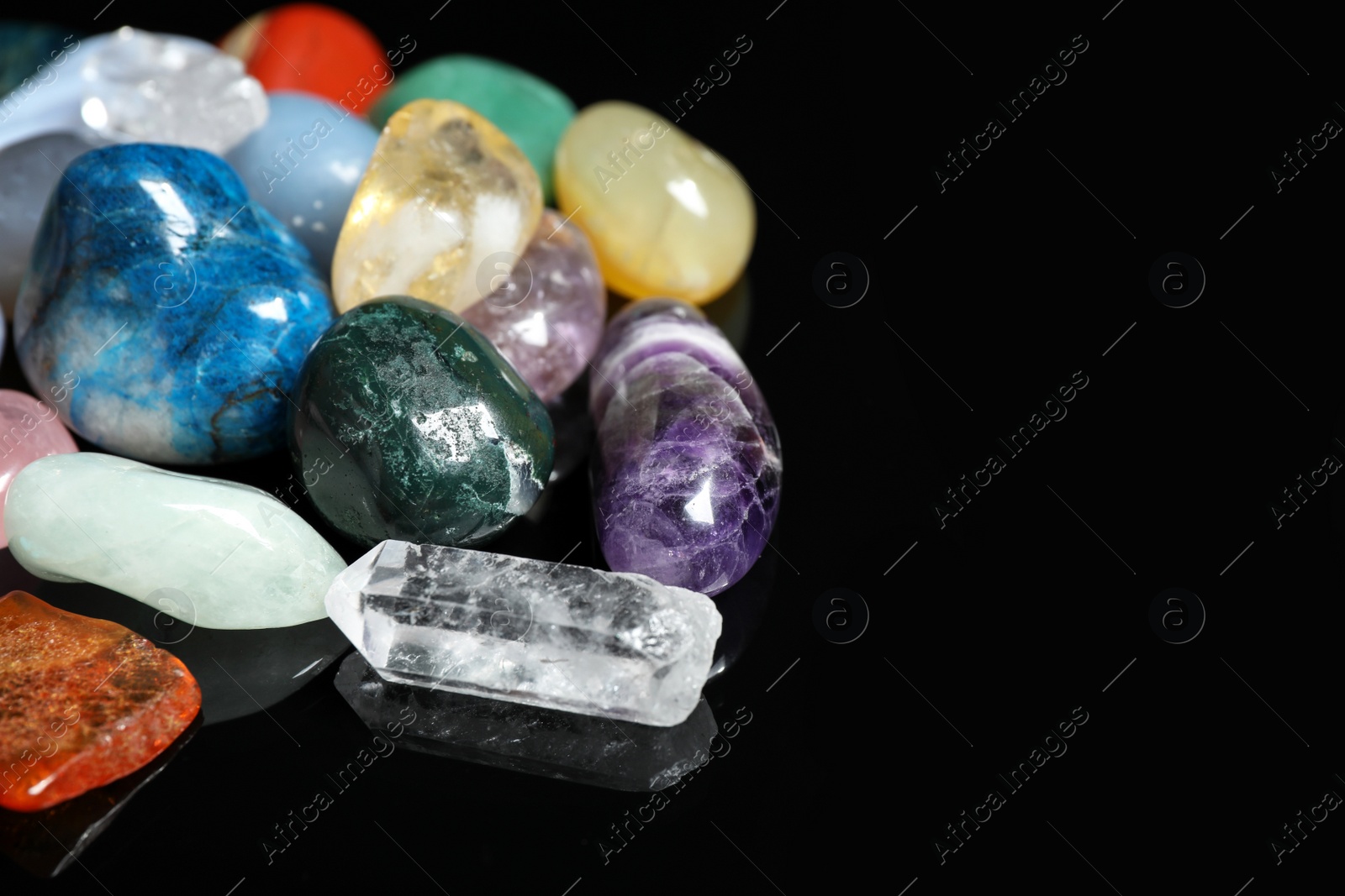 Photo of Different beautiful gemstones on black background, closeup. Space for text