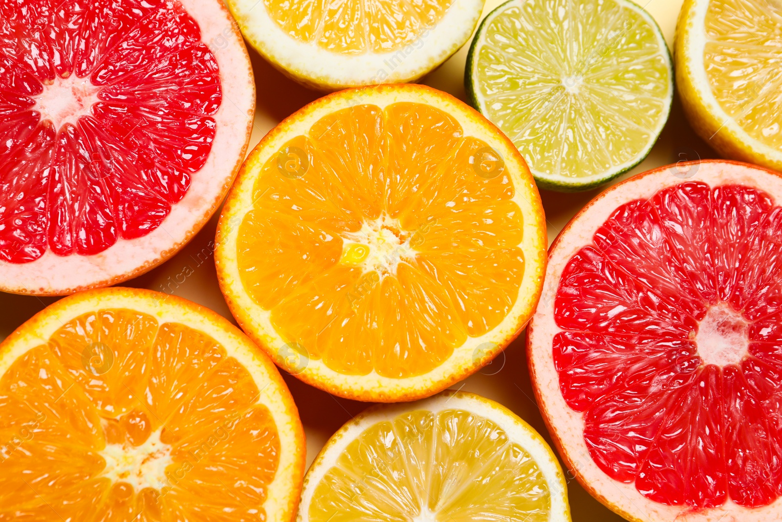 Photo of Different cut citrus fruits on beige table, flat lay