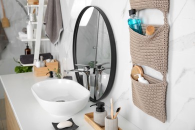 Photo of Knitted organizer hanging on wall in bathroom