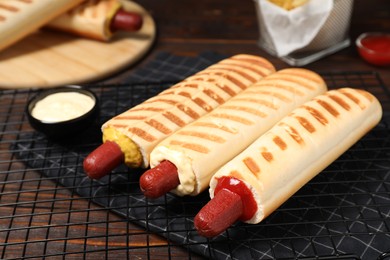Delicious french hot dogs and dip sauce on wooden table, closeup