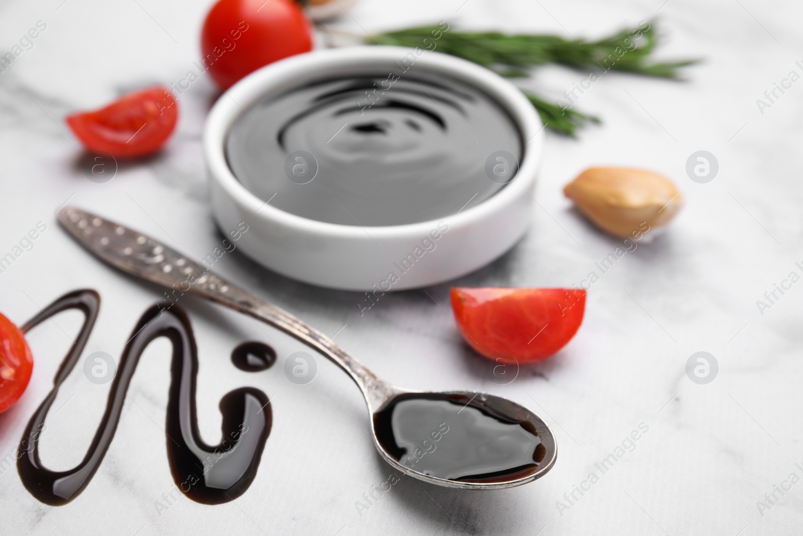 Photo of Organic balsamic vinegar and cooking ingredients on white marble table, closeup