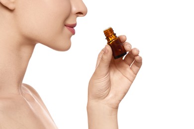 Young woman smelling essential oil on white background, closeup