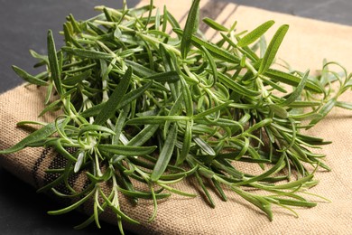 Photo of Aromatic green rosemary sprigs on burlap, closeup