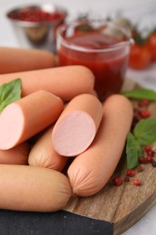 Photo of Delicious boiled sausages, basil and peppercorns on table, closeup