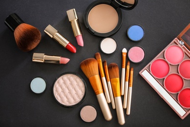 Flat lay composition with makeup brushes and cosmetic products on black background