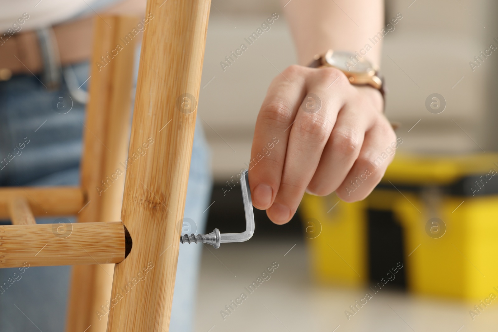 Photo of Woman with hex key assembling furniture indoors, closeup