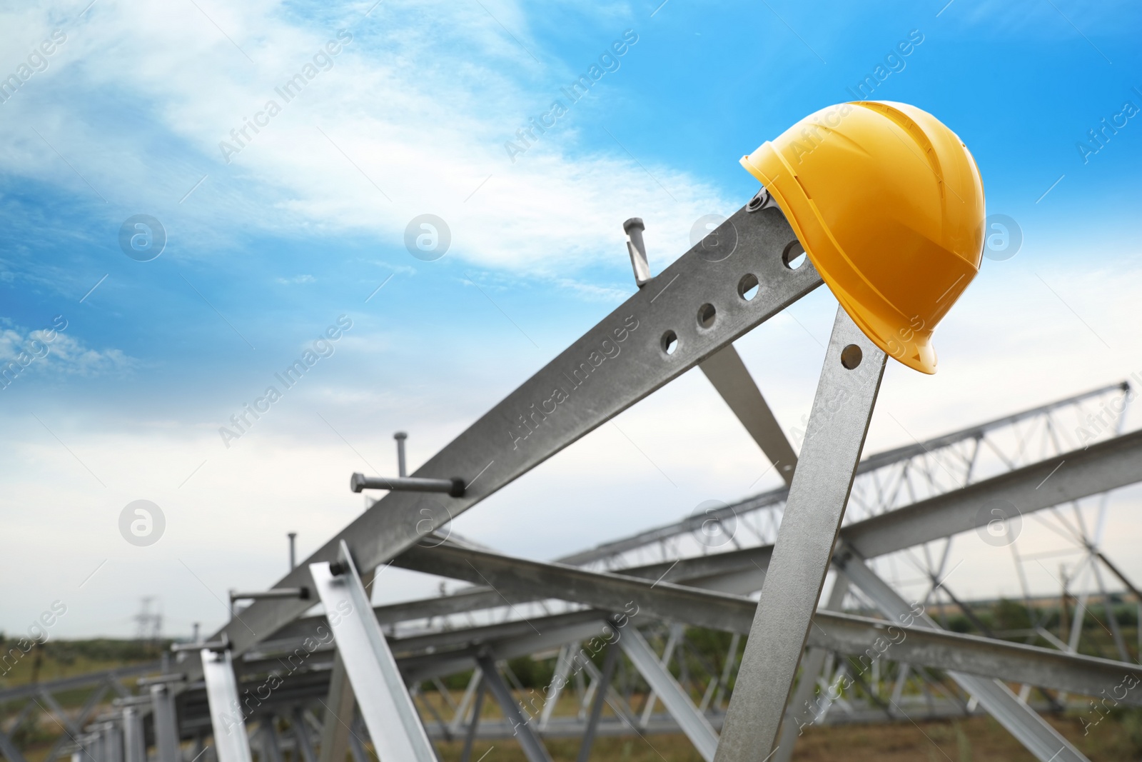 Photo of High voltage tower construction with yellow hard hat outdoors. Installation of electrical substation