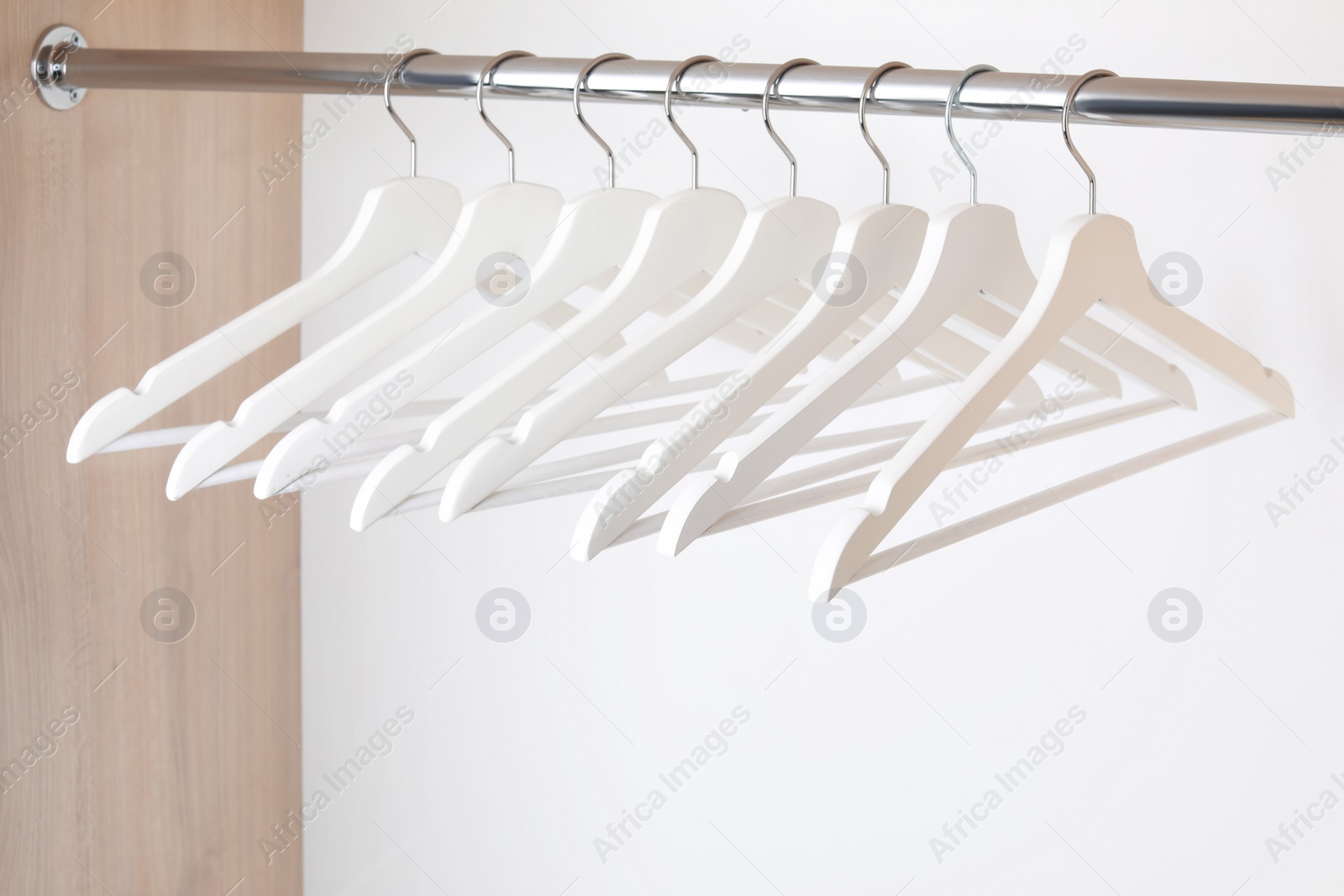 Photo of Clothes hangers on metal rail in wardrobe