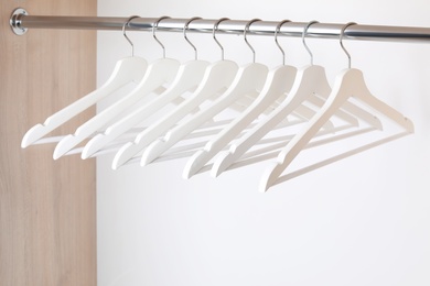 Photo of Clothes hangers on metal rail in wardrobe