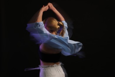 Photo of Young woman performing contemporary dance on black background, motion blur effect