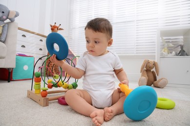 Photo of Cute baby boy playing with toys on floor at home