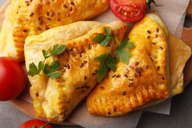 Fresh delicious puff pastry with cheese, tomatoes and parsley on grey table, top view
