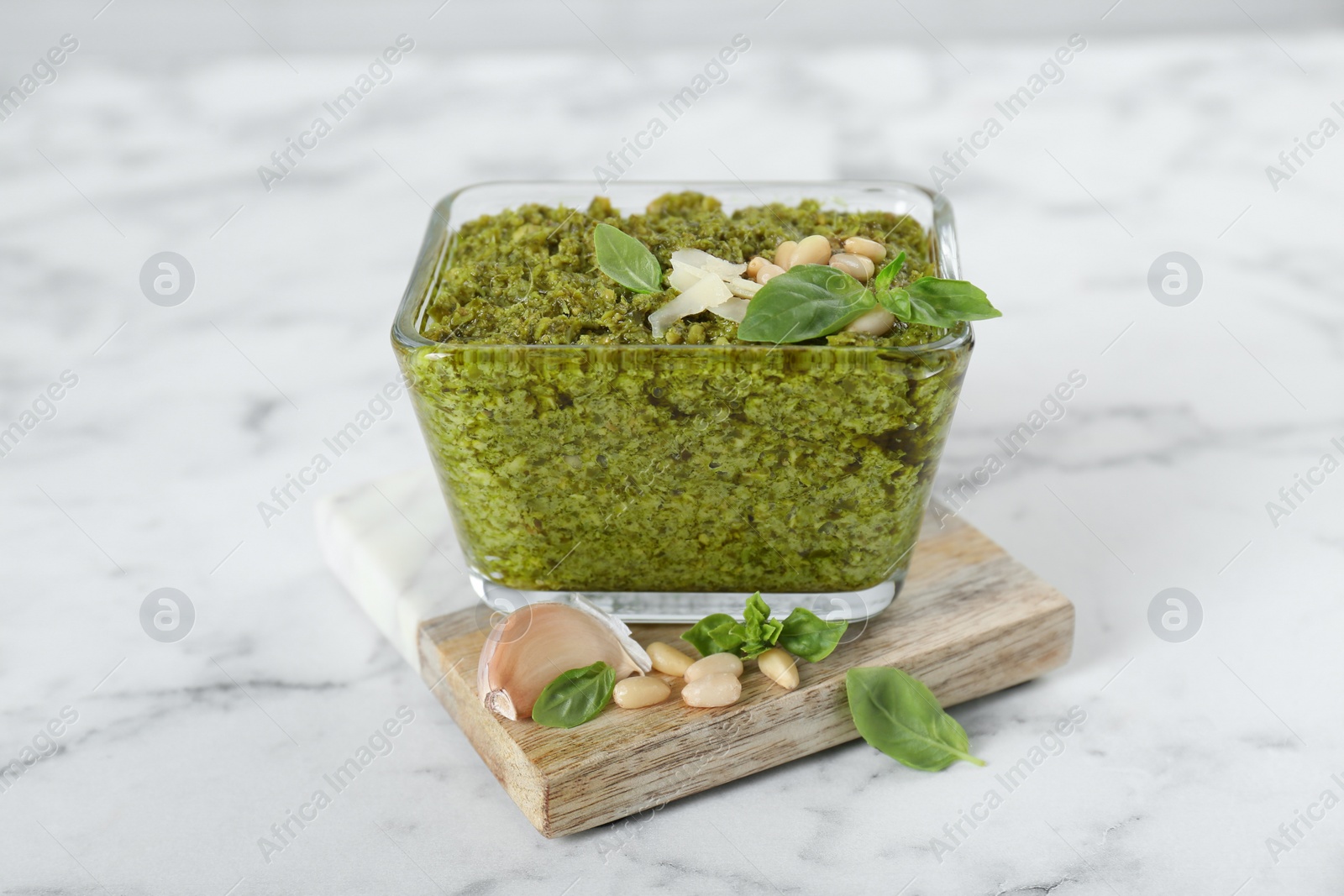 Photo of Delicious pesto sauce in bowl on white marble table, closeup