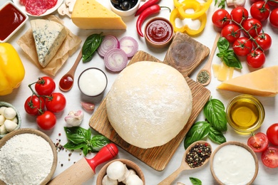 Photo of Flat lay composition with dough and fresh ingredients for pizza on white wooden table