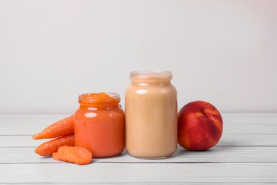 Photo of Jarshealthy baby food and ingredients on white wooden table, closeup