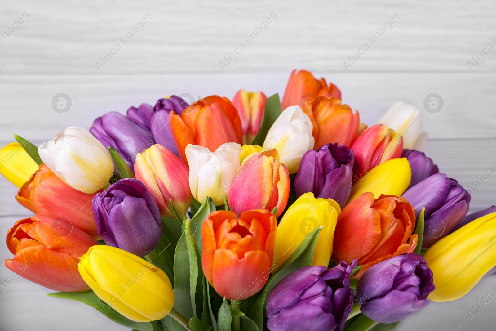 Photo of Bouquet of beautiful colorful tulips on white wooden background, closeup