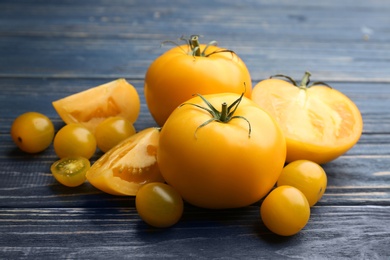 Photo of Ripe yellow tomatoes on blue wooden table