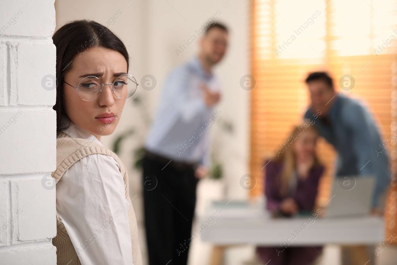 Photo of Coworkers bullying their colleague in office, space for text
