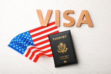 Photo of Flat lay composition with flag of USA, passport and word VISA on wooden background