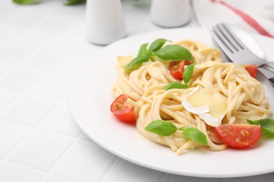 Photo of Delicious pasta with brie cheese, tomatoes, basil and cutlery on white tiled table, closeup. Space for text