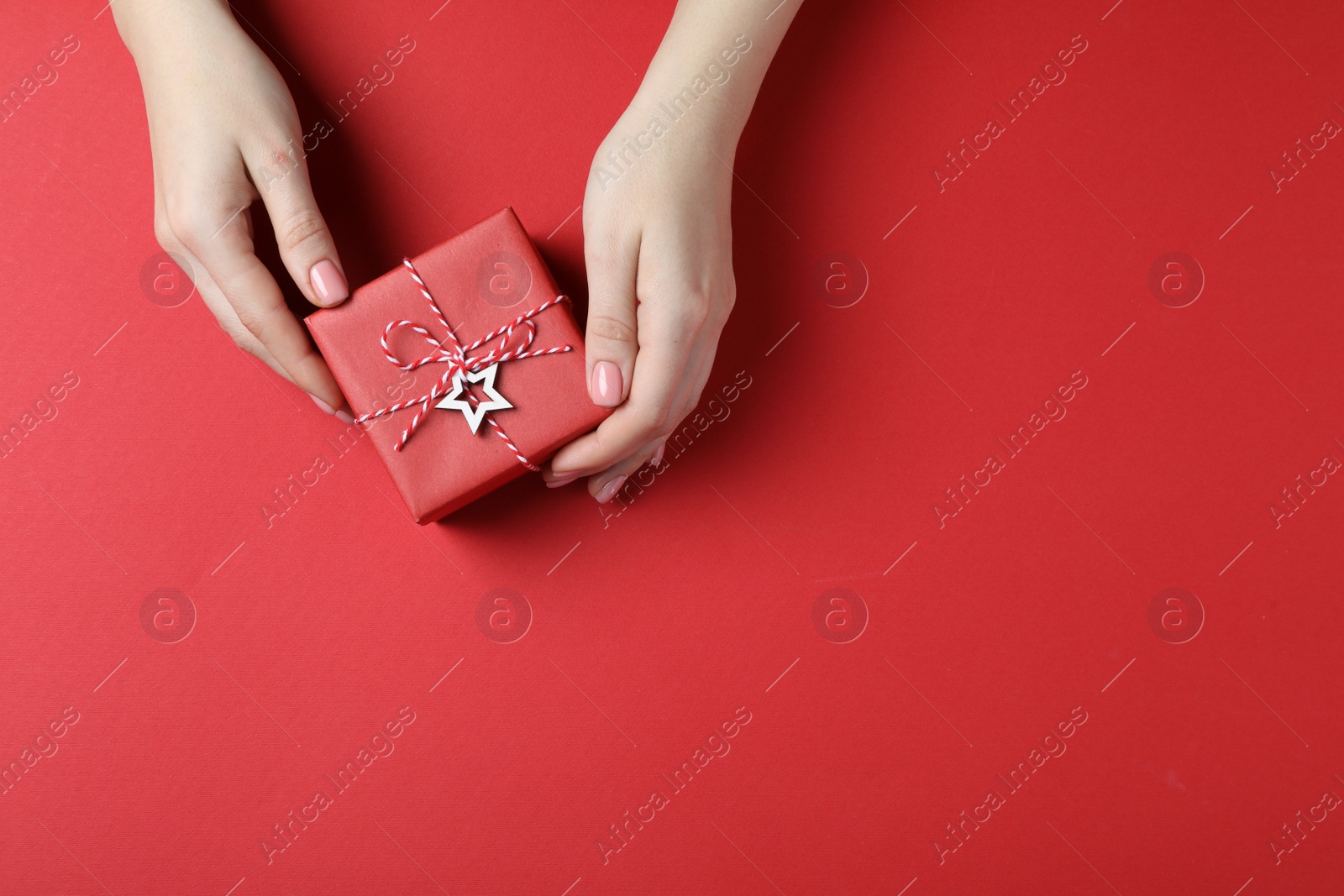 Photo of Woman with beautifully wrapped Christmas gift box on red background, top view. Space for text