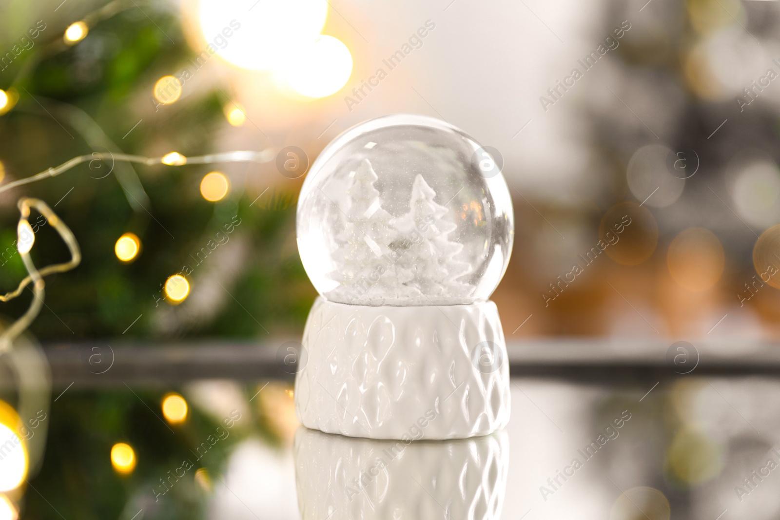 Photo of Decorative Christmas snow globe on mirror surface