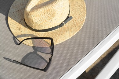 Stylish hat and sunglasses on grey sunbed outdoors, above view