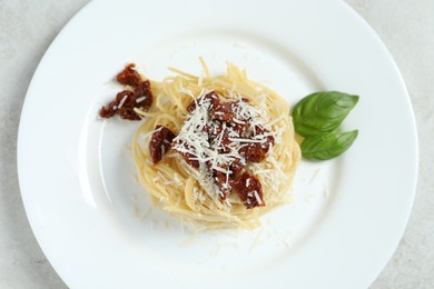 Photo of Tasty spaghetti with sun-dried tomatoes and parmesan cheese on white table, top view. Exquisite presentation of pasta dish