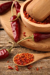 Chili pepper flakes and pods on wooden table