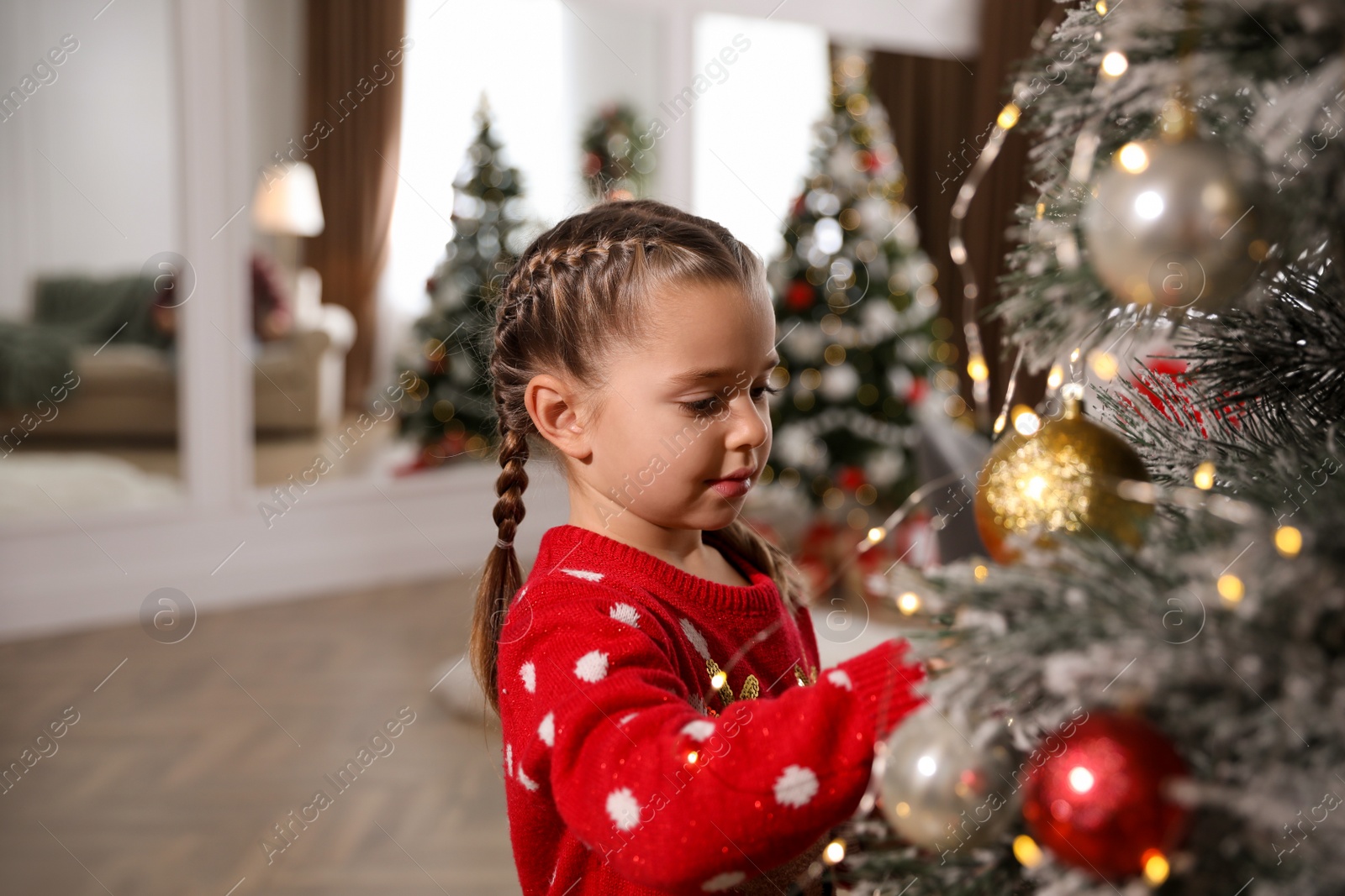 Photo of Adorable little child decorating Christmas tree at home