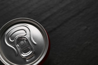 Photo of Energy drink in can on black textured background, top view. Space for text