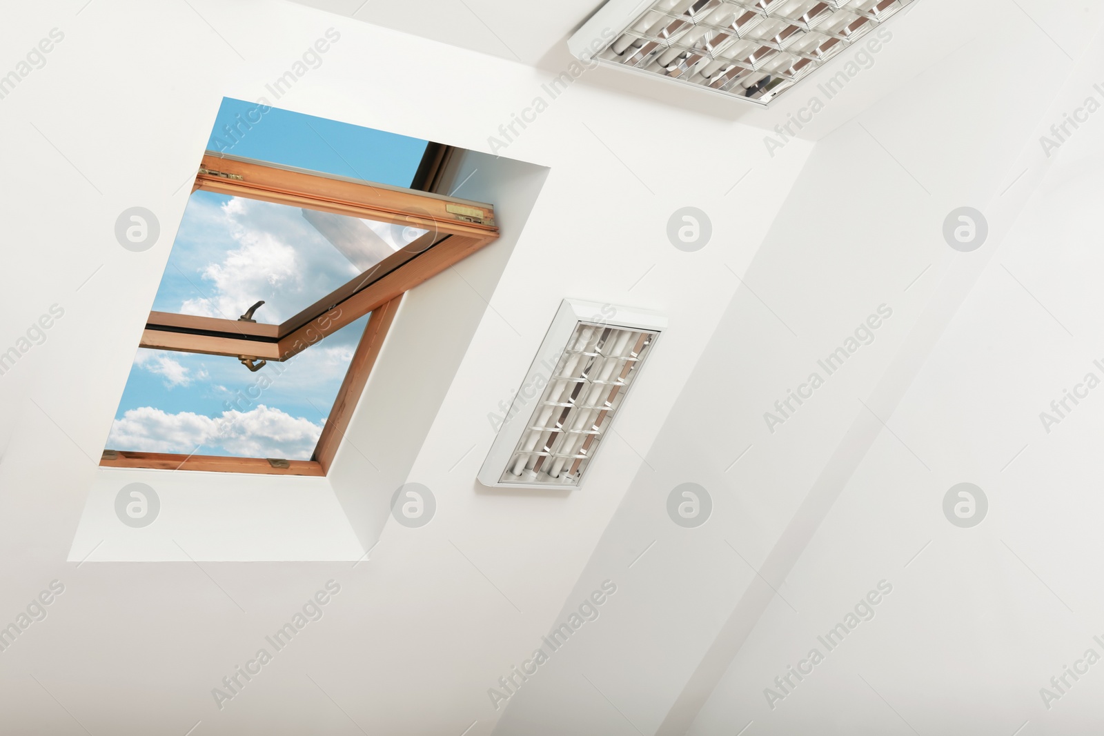 Photo of Open skylight roof window on slanted ceiling in attic room, low angle view