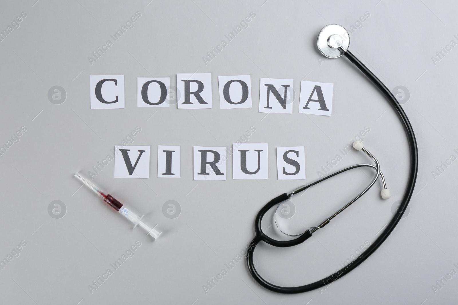 Photo of Flat lay composition with words CORONA VIRUS, stethoscope and syringe on light grey background