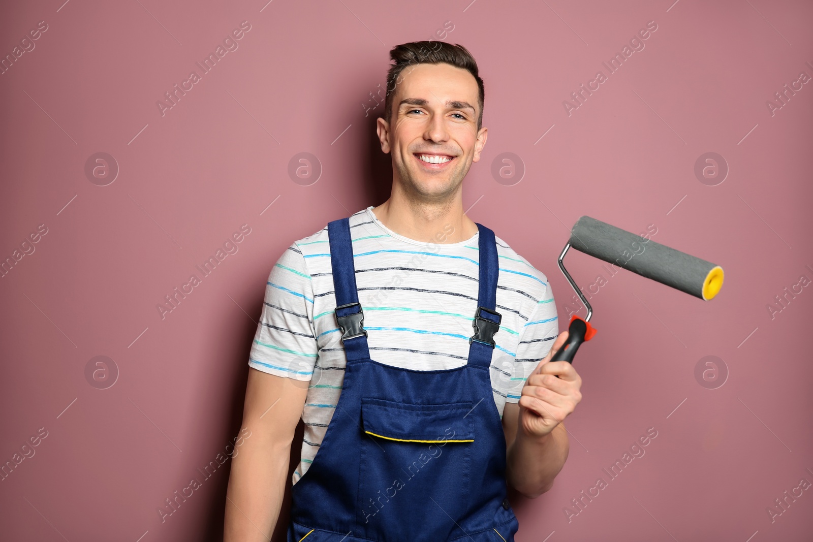 Photo of Young male decorator with paint roller near color wall