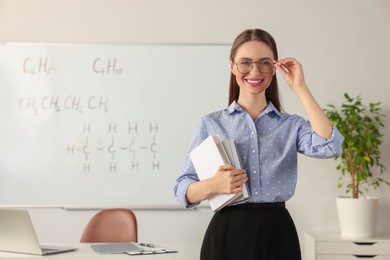 Photo of Portrait of young chemistry teacher near whiteboard in classroom. Space for text