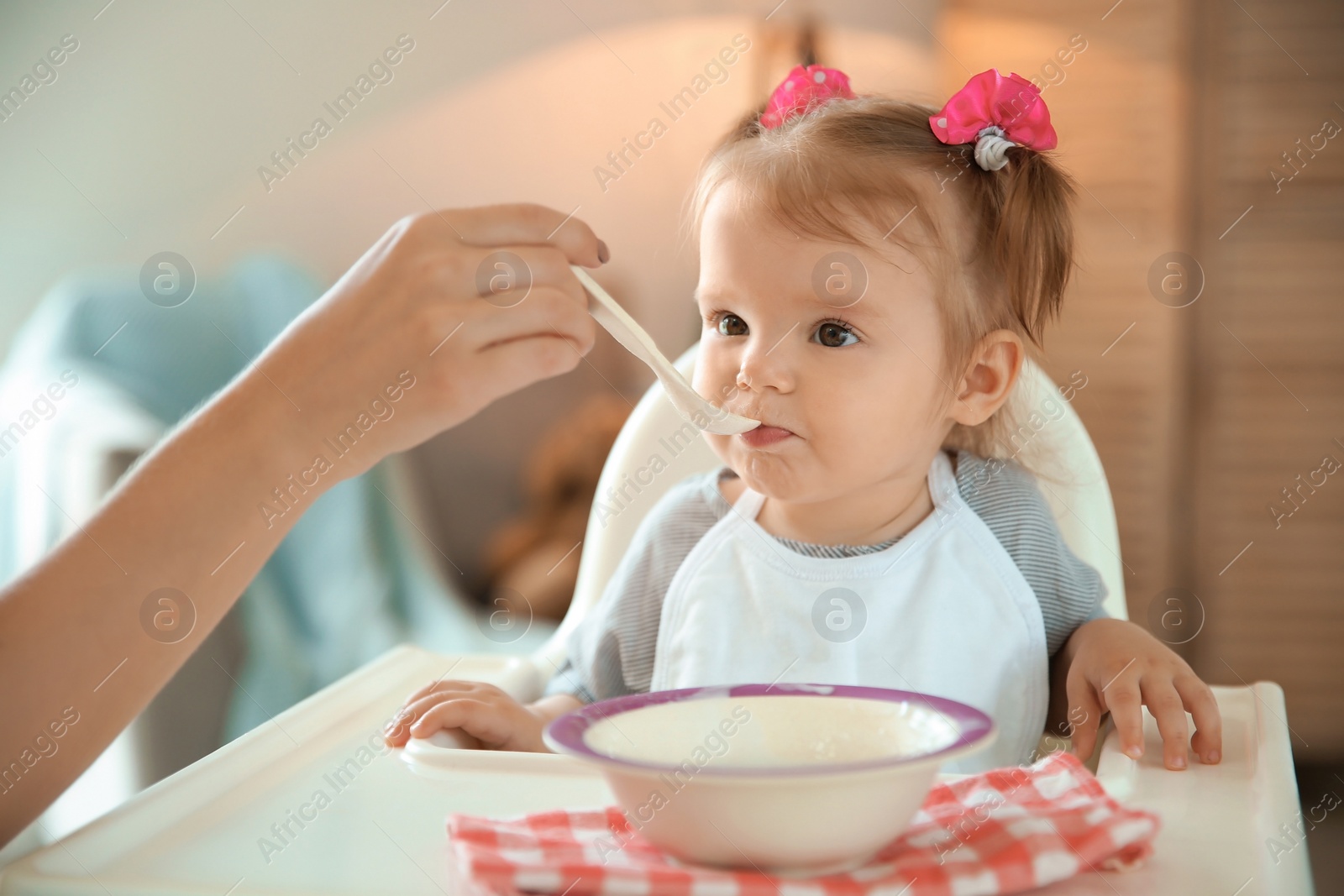 Photo of Caring mother feeding her cute little baby with healthy food at home