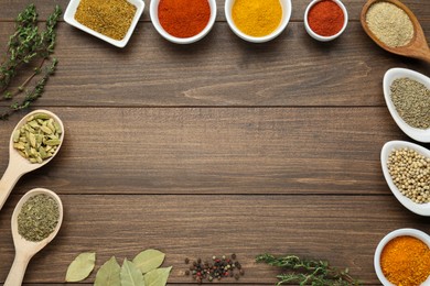 Many different spices on wooden table, flat lay. Space for text