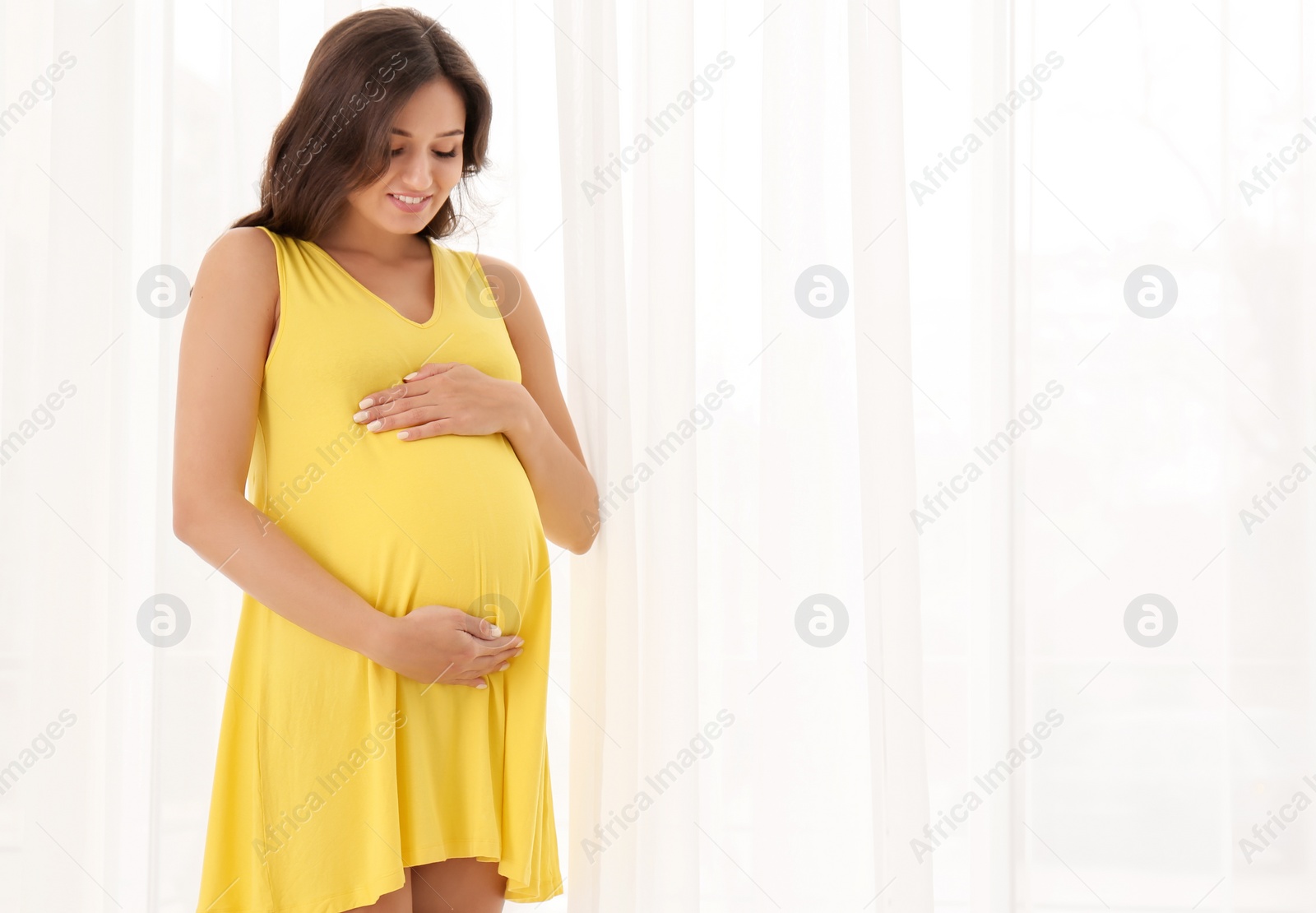 Photo of Beautiful pregnant woman near window at home