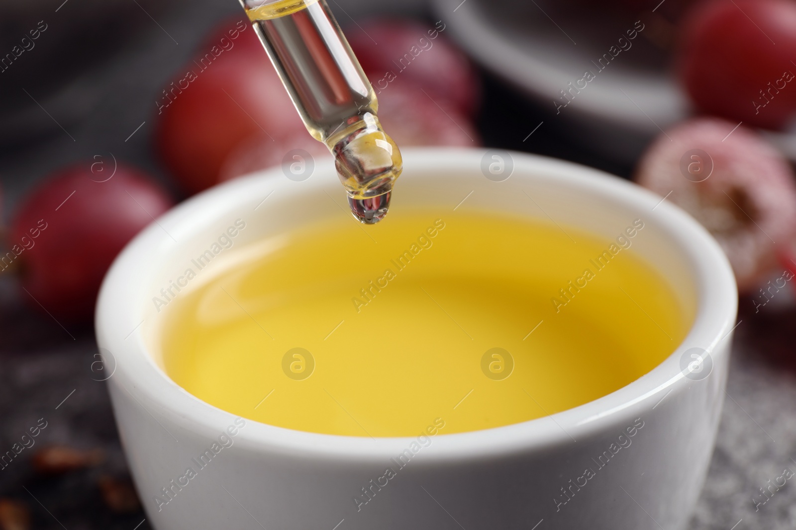 Photo of Dripping natural grape seed oil into bowl, closeup. Organic cosmetic