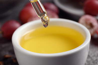 Dripping natural grape seed oil into bowl, closeup. Organic cosmetic